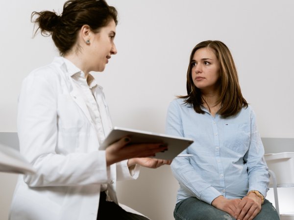 Individual in white coat sharing information with another person.
