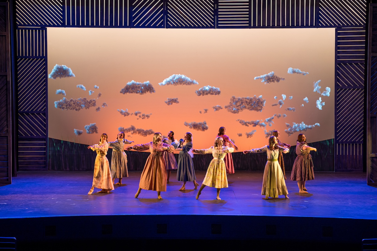 Multiple dancers performing on a blue stage