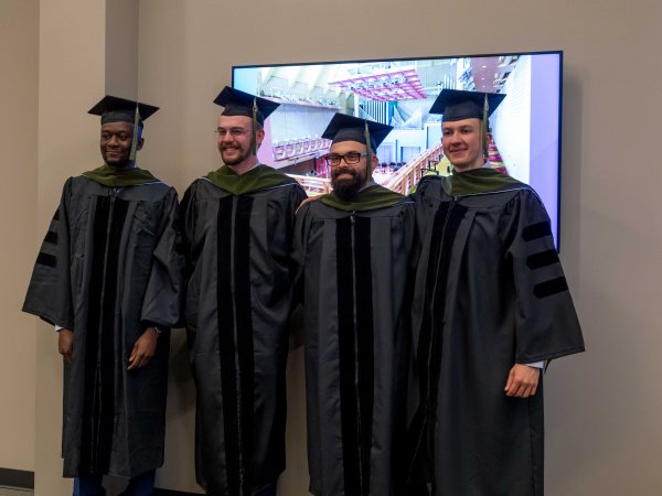 Four students in graduation cap and gown