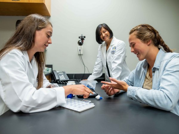 Student and faculty demonstrating how to check blood sugar