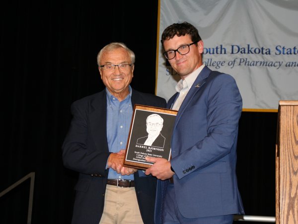 Darrel Bjornson, left, receives the Distinguished Alumni plaque from Dean Dan Hansen at the college’s Sept. 11 scholarship luncheon. Bjornson, class of 1967, split his career between the U.S. Army and Drake University.