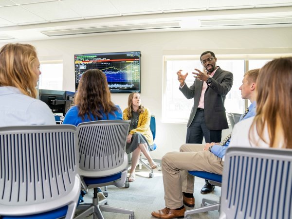 Professor speaking to a group of students in a finance lab.