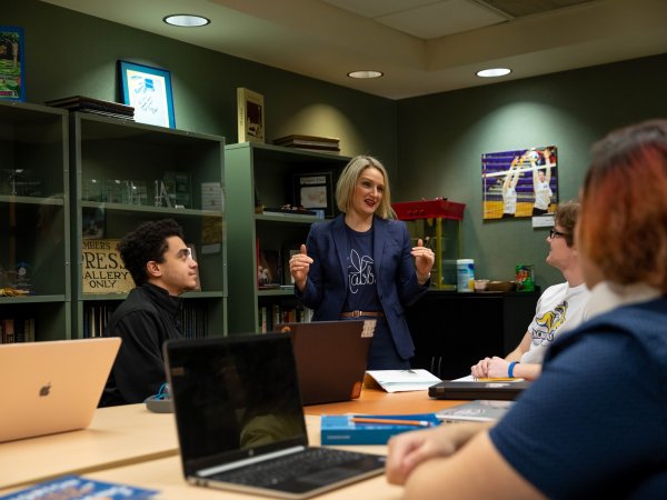 Instructor leading a conversation with a small group of students in a conference room.