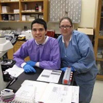 student and instructor in a lab with a microscope