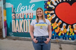 Student standing in front of I love South Dakota mural.