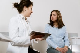 Individual in white coat sharing information with another person.