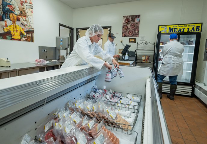 Workers placing meat in the cooler at the SDSU Meat Lab.