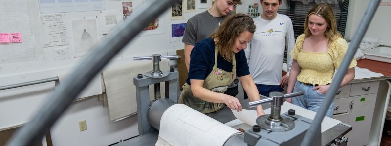 Three students and instructor in a printmaking lab.