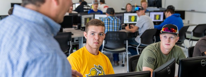 Students sitting at computers in a precision agriculture classroom listening to the instructor.