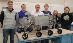 SDSU mechanical engineering students who qualified for the finals of a NASA contest are, from left, Braxton McGrath, Aiden Carstensen, graduate adviser Liam Murray, Dylan Stephens, Delaney Baumberger and Alex Schaar. They are pictured with a prototype of a rover designed to explore rugged, frozen lunar craters.