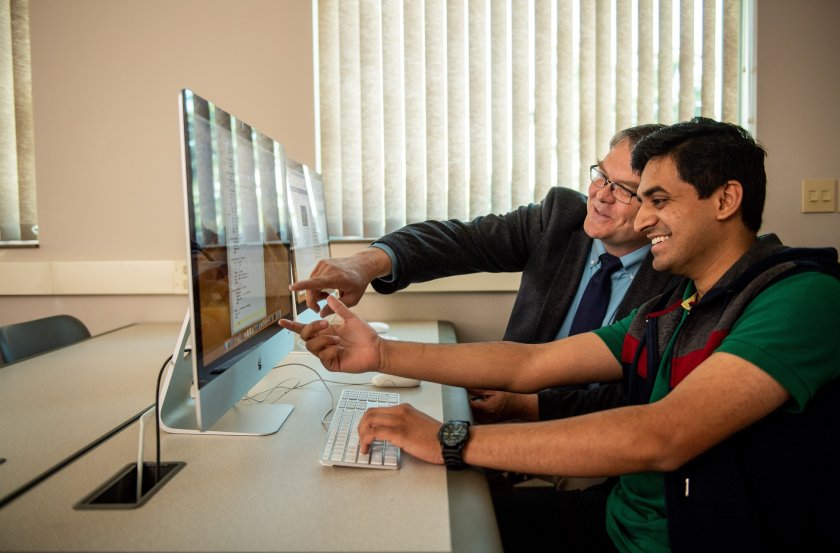 Student and professor looking at a computer monitor.