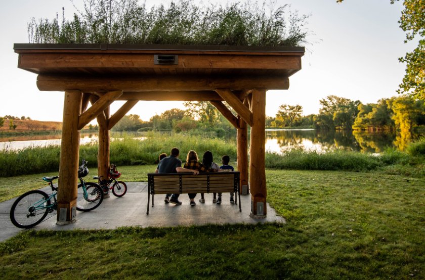 A family of five sits on a bench at a nature park