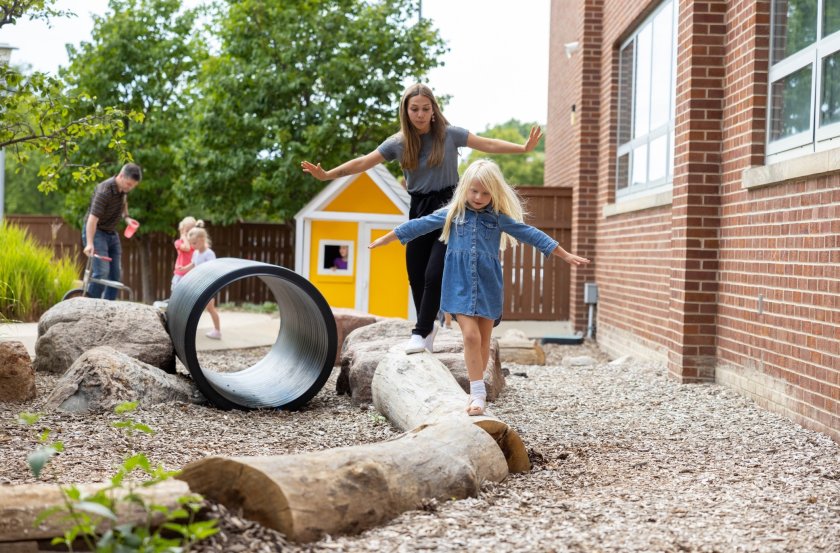 Student teacher and child playing on log